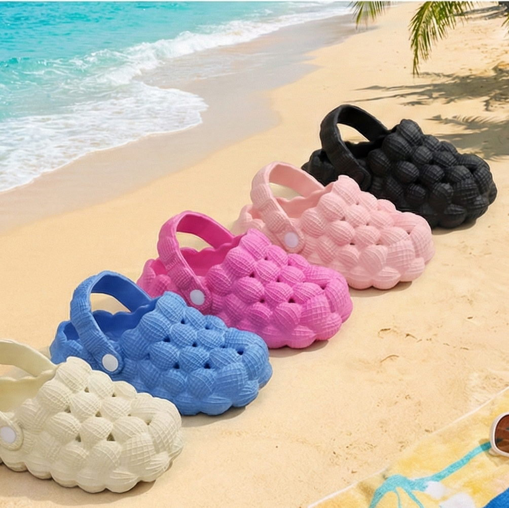 Colorful clogs on a sandy beach with ocean in the background